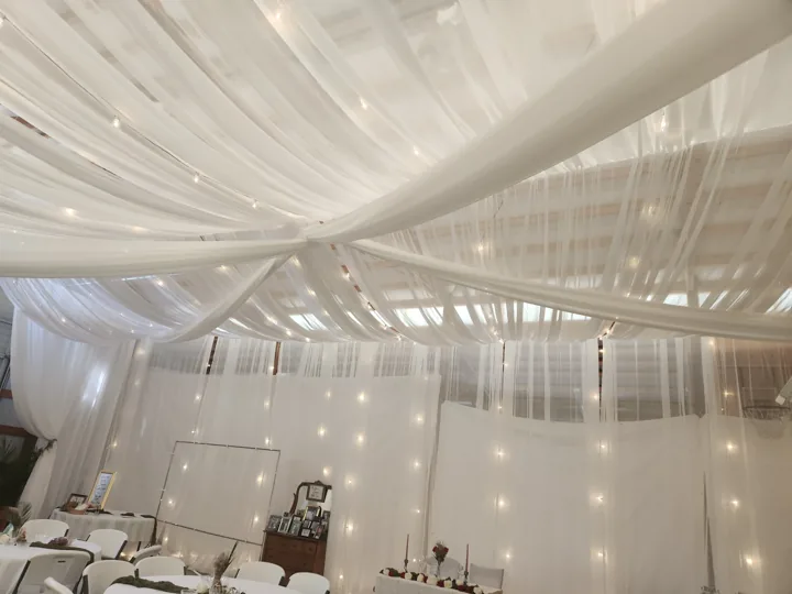 An intimate workshop space transformed with draping, lights and round tables.