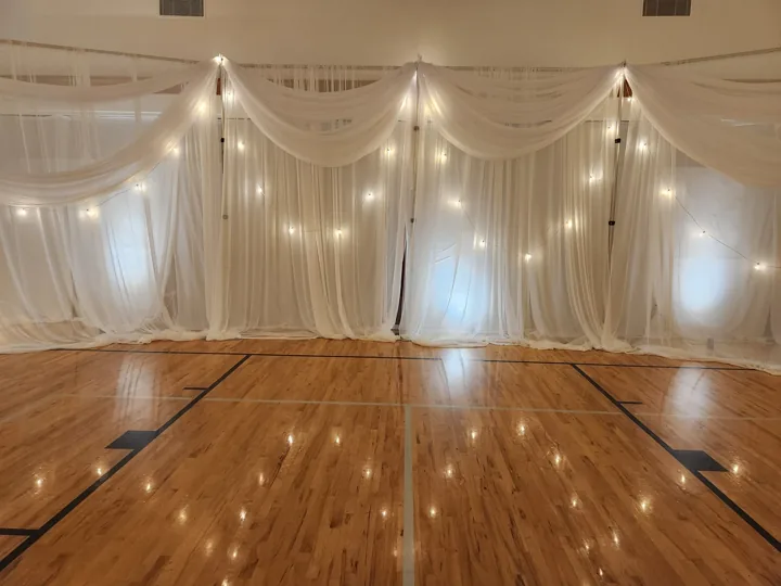 An end-wall focal point with accent drapes and string lights.