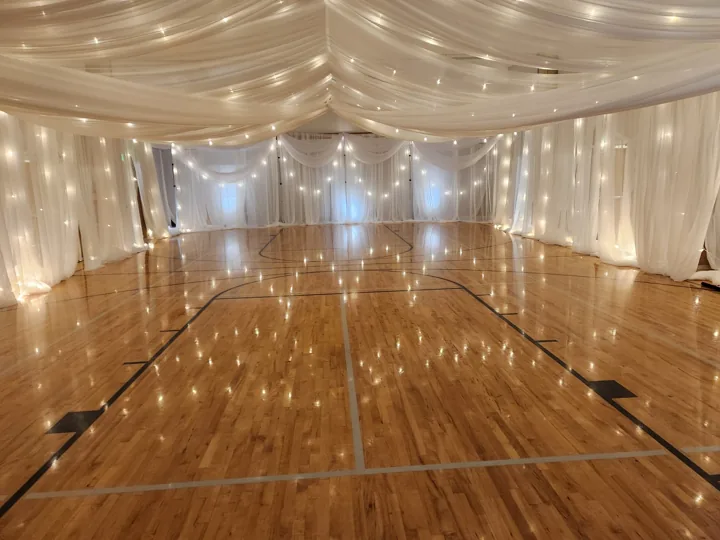Actual BSS canopy installation with string lights, a draped end wall, accent swags and blue uplighting before furniture is placed.
